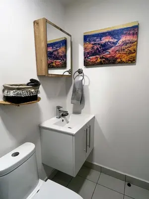 a bathroom with a white toilet and a mirror at Top-floor overlooking uptown with AC & parking in San José