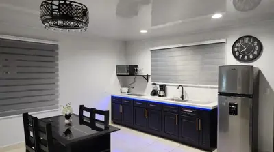a kitchen with a stainless steel refrigerator and a clock at Tropical Noir at Family Lodge in Jabillos