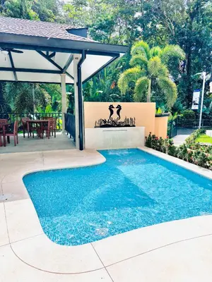 a swimming pool in front of a house with a patio at Apartamento en condominio Torres del Mar, Jacó in Jacó