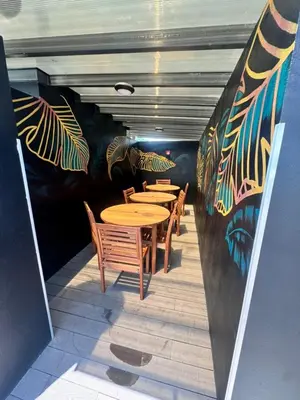 a row of tables and chairs with a mural on a wall at Apartamento en condominio Torres del Mar, Jacó in Jacó