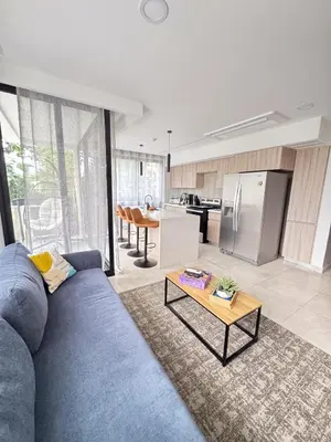 a living room with a blue couch and a kitchen at Apartamento en condominio Torres del Mar, Jacó in Jacó