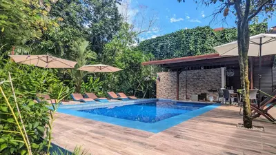 an outdoor swimming pool with chairs and umbrellas at Jardín de los Monos in Matapalo