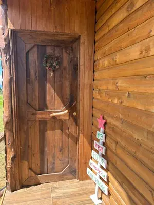 a wooden cabin with a door with signs on it at Cabaña Rancho Don Marino in Cartago