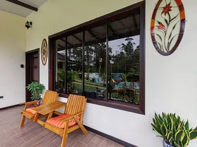 a patio with two chairs and a table and a window at La Finca Tovar- Casita in San Ramón