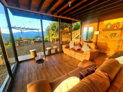 a living room with a couch and a large window at Glamping Los tucanes in San José