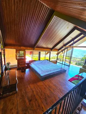 a bedroom with a bed on a wooden floor at Glamping Los tucanes in San José