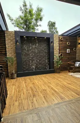 a patio with a brick wall and a wooden floor at Glamping Los tucanes in San José