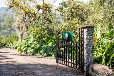 a gate with a sign on it in a garden at BYB Finca Chiribita - Idyllisch I Herzlich I Persönlich - Der Charme des Kleinen in Orosí