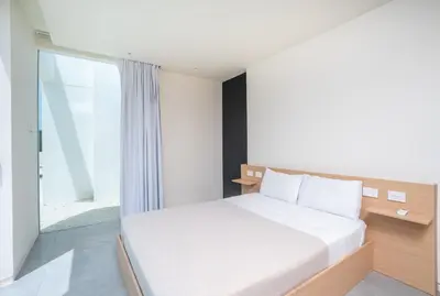a bedroom with a white bed and a window at Villa Juba Tamarindo Centro in Tamarindo