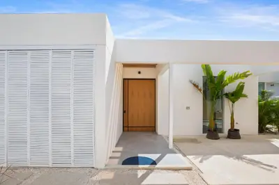 a white house with a wooden door at Villa Juba Tamarindo Centro in Tamarindo