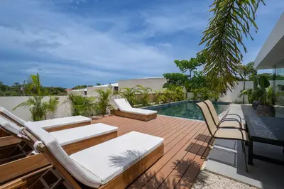 a deck with lounge chairs and a swimming pool at Villa Juba Tamarindo Centro in Tamarindo
