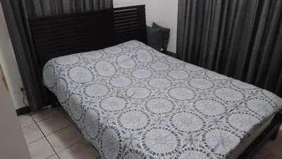 a bed with a white comforter on top of it at Rincón Metropolitano in San José