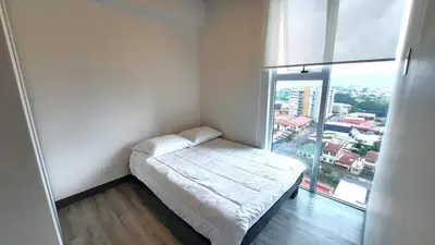 a small bedroom with a bed and a large window at Sabana Chic in Hatillo