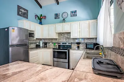 a kitchen with white cabinets and a stainless steel refrigerator at Casa Mariposa in Jacó