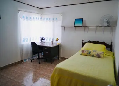 a bedroom with a bed and a desk with a computer at Pura Vida Tico Casita in Barva