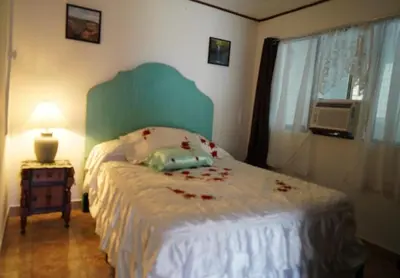 a bedroom with a bed with red flowers on it at Pura Vida Tico Casita in Barva