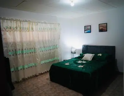 a bedroom with a bed with a green comforter at Pura Vida Tico Casita in Barva