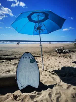 a surfboard sitting in the sand next to an umbrella at Casa Lucas in Villarreal