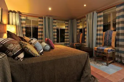 a bedroom with a bed with pillows and a chair at Villa Turrubares in San Pablo