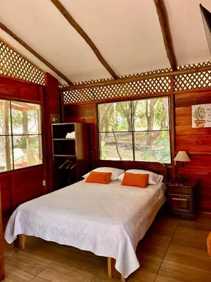 a bedroom with a bed with two orange pillows at Casa LORA Eco nature retreat in Bagaces in Bagaces