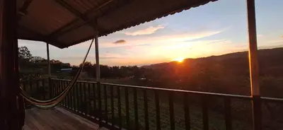 a hammock on a deck with the sunset in the background at Mountain & sunset view Villa, Monteverde in Monteverde Costa Rica