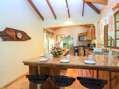 a kitchen with a large counter with stools at Casa Colibrí Playa Grande in Santa Cruz