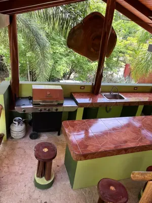a kitchen with a sink and a table and stool at Casa Colibrí Playa Grande in Santa Cruz