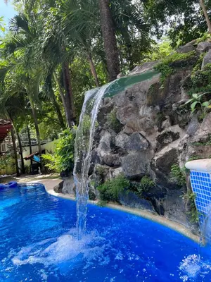 a swimming pool with a waterfall in a resort at Casa Colibrí Playa Grande in Santa Cruz