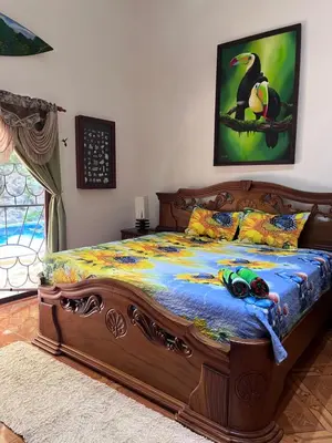 a bedroom with a large wooden bed with a bird on it at Casa Colibrí Playa Grande in Santa Cruz