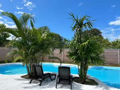 two chairs and palm trees next to a swimming pool at Bravo paraiso azul beach house in Savegre