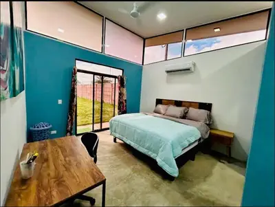 a bedroom with a bed and a table and a window at Bravo paraiso azul beach house in Savegre