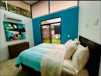 a bedroom with a large bed with a blue wall at Bravo paraiso azul beach house in Savegre