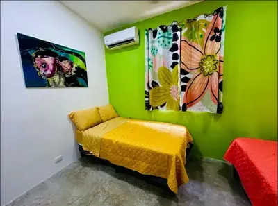a green room with a bed and two paintings at Bravo paraiso azul beach house in Savegre
