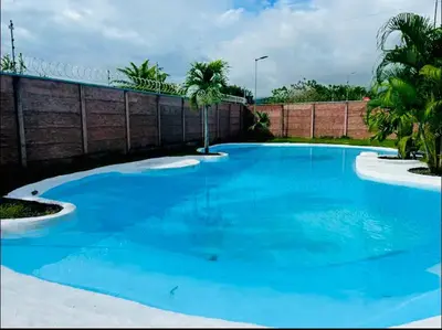 a large blue swimming pool with a fence and palm trees at Bravo paraiso azul beach house in Savegre