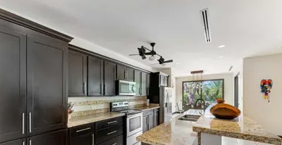 a large kitchen with black cabinets and a sink at Luxe, Playa del Coco, Pacific in Coco