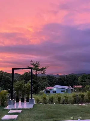 a sunset over a field with a house in the background at Casa Nara in Sámara