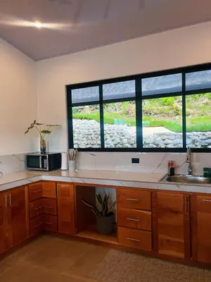 a kitchen with wooden cabinets and a large window at Casa Nara in Sámara