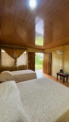 a large bedroom with two beds and a window at Cabinas Caño Negro in Los Chiles