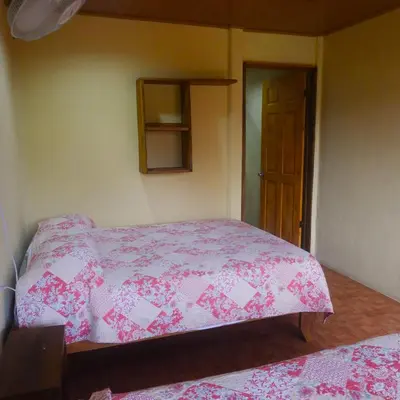 a bedroom with a bed with a pink bedspread at Cabinas Caño Negro in Los Chiles