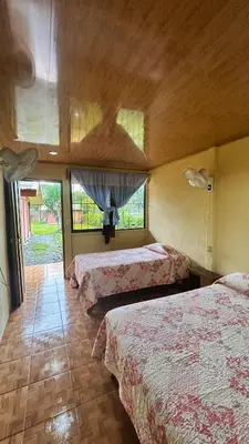a hotel room with three beds and two windows at Cabinas Caño Negro in Los Chiles