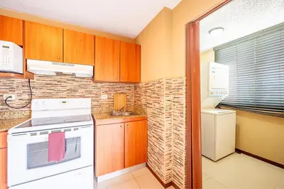 a kitchen with wooden cabinets and a white stove top oven at 2-17 Jaco Beach Beautiful Costa Linda Condo in Jacó