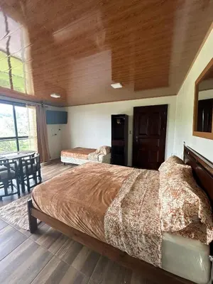 a bedroom with a large bed and a table at Cabaña en Riverland in Zarcero