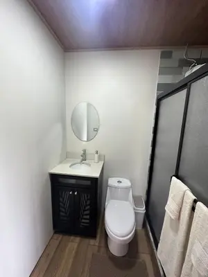 a bathroom with a toilet and a sink and a mirror at Cabaña en Riverland in Zarcero