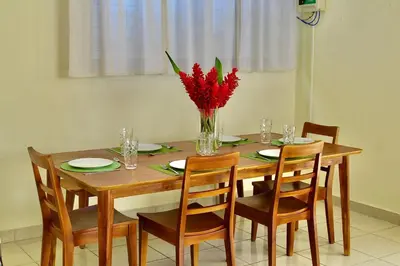 a dining room table with a vase of red flowers at Villa de Playa, Paseo de los Turistas in Puntarenas