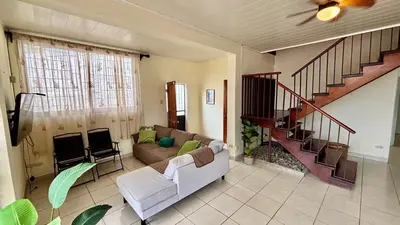 a living room with a couch and a staircase at Villa de Playa, Paseo de los Turistas in Puntarenas