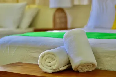 a roll of white towels sitting on a table next to a bed at Villa de Playa, Paseo de los Turistas in Puntarenas