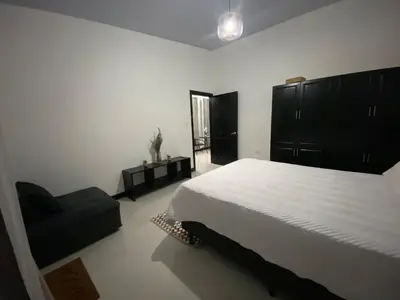 a bedroom with a large bed and a chair at Sarahs Villas in Parrita