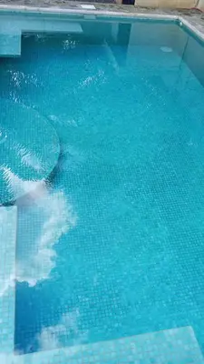 a blue swimming pool with a reflection in the water at Sarahs Villas in Parrita