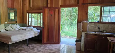 a bedroom with a bed and a sink and windows at Cabaña Rio Diamante in Barú