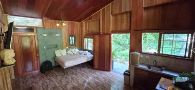 a room with a bed and some wood walls and windows at Cabaña Rio Diamante in Barú